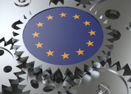 A cog embossed with the EU flag sits on top of a series of other cogs 