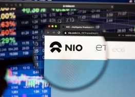 KAUFBEUREN, GERMANY - APRIL 19, 2021: Nio electric car company logo on a website with blurry stock market developments in the background, seen on a computer screen through a magnifying glass.